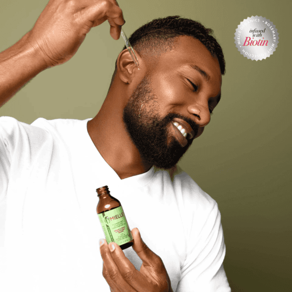 Man applying mielle scalp and hair strengthening oil.