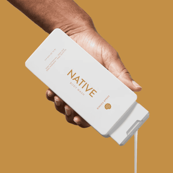 Arm pouring a bottle of Native limited edition holiday scent sugar cookie body wash.