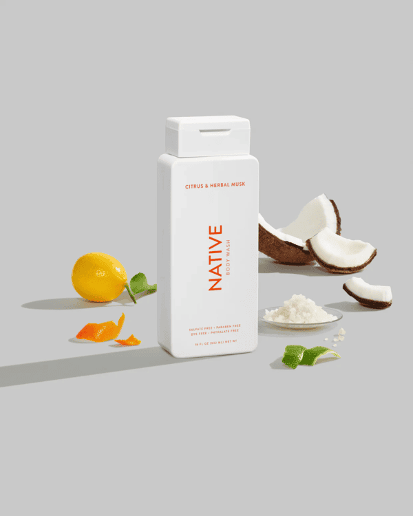 Bottle of native citrus herbal musk body wash with raw ingredients.